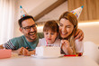 © Nebojsa - Happy parents are wearing birthday caps while they are celebrating daughters birthday in their home
