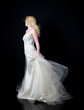 © faestock - full length portrait of woman wearing white bridal gown. standing poison black studio background.