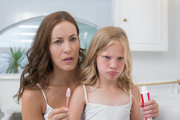 Wall Mural - Mother and displeased daughter with toothbrush and toothpaste