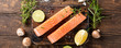 Flat lay with fresh raw salmon fillet and aromatic herbs, spices, pepper, salt, mushrooms lemon and rosemary. Old wooden background. Top view. Banner.