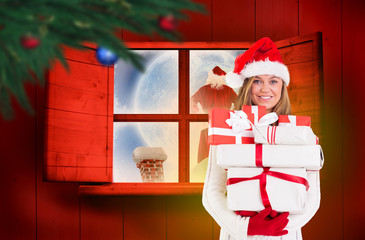 Wall Mural - Festive blonde holding pile of gifts against festive fir branch with baubles 