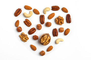 Different kinds of nuts laid out in the shape of a heart, isolated on white background.