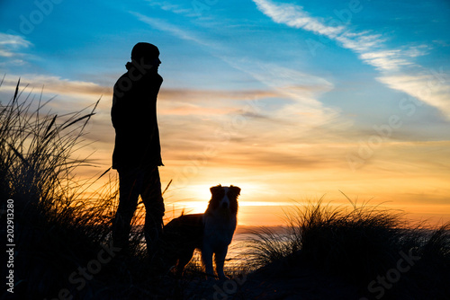 Silhouette Von Einem Mann Und Einen Hund Am Strand Bei Sonnenuntergang Umrahmt Von Grasern Kaufen Sie Dieses Foto Und Finden Sie Ahnliche Bilder Auf Adobe Stock Adobe Stock