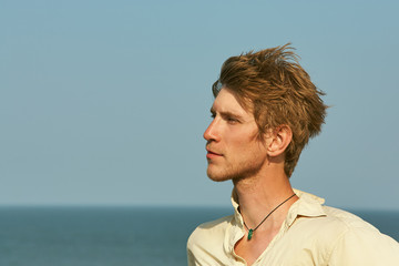 Portrait of a young smiling man on blue background. people in the summer outdoors