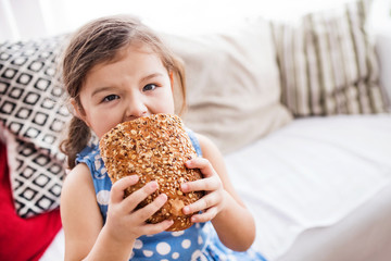 Wall Mural - A small girl at home eating a loaf of bread.