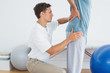 © WavebreakmediaMicro - Therapist massaging mans lower back at hospital gym