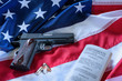 The second amendment and gun control in the US, concept. A handgun, bullets, and the american constitution on the USA flag.