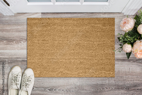 Blank coir doormat before the door in the hall. Mat on wooden floor, flowers and shoes. Welcome home, product Mockup © maddyz