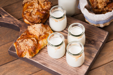 Wall Mural - Bread buns, jars with milk on a cutting board 