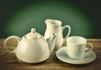 Wall Mural - white ceramic coffee set on old wooden table over green background