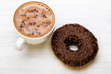 Cup of coffee and tasty donuts with icing and chocolate on white wooden background, copy space