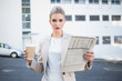 © WavebreakmediaMicro - Serious stylish businesswoman holding newspaper and coffee