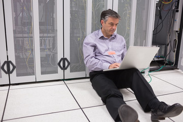 Aufkleber - Man sitting on floor using laptop to check the servers
