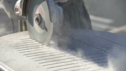 Wall Mural - Worker in gloves with a big angle grinder cuts a granite slab. Stone processing from rock.