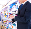 © vectorfusionart - Mid section of a businessman with arms out against close up of shelves of drugs