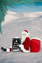 Santa Sits Leaned On His Bag With A Board Against Digitally Generated Snowy Land Scape