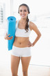 © WavebreakmediaMicro - Happy sporty woman holding a balled up exercise mat