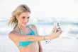 © WavebreakmediaMicro - Cheerful sexy blonde in bikini taking a self picture