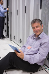 Aufkleber - Smiling man sitting on the floor with his tablet beside servers