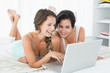 © WavebreakmediaMicro - Relaxed smiling friends using laptop in bed