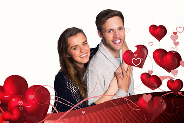 Portrait of happy young couple against valentines heart design