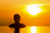 Fototapeta  - Sunset for freedom concept with woman in the water and beautiful silhouette.  Totally free and living a healthy life.