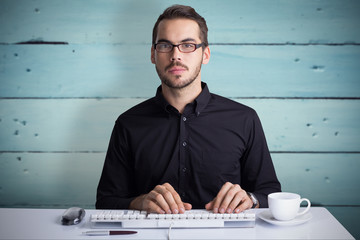 Canvas Print - Focused businessman typing on keyboard  against painted blue wooden planks