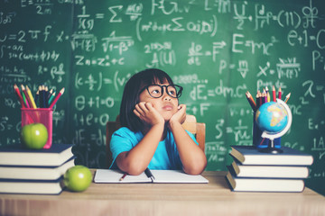 Wall Mural - Thoughtful little girl with book near a school board