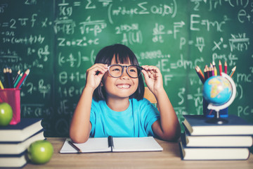 Wall Mural - Thoughtful little girl with book near a school board