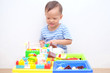 © yAOinLoVE - Cute little Asian 18 months / 1 year old toddler boy child sitting on wooden floor having fun playing with colorful building blocks indoor at home, Educational toys for young children concept