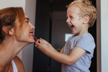 little boy putting on makeup to her mother