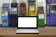 © MemoryMan - Laptop with blank screen on wooden table with atm banking machine in background.internet shoping online and business payment concept