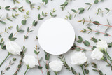 Minimalistic mockup of white flowers and eucalyptus leaves on gray table top view. Flat lay style.