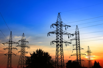 High-voltage power lines at sunset. Electric transmission towers.