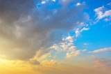 Fototapeta Zachód słońca - Fluffy cumulus clouds before sunset on a beautiful sky gradient from blue to orange.
