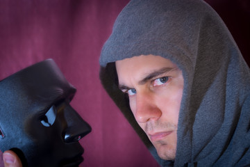 a mask in the hand of a young man who looks at the camera