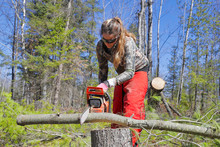 A Young Female Using A Chainsaw.