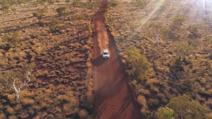aerial view of vehicle driving on dirt road through the australia outback in the desert of karijini 