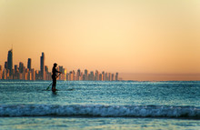 Single Paddler Against The Gold Coast Skyline At Sunset.
