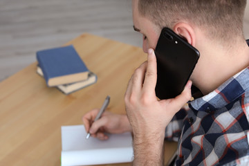 Wall Mural - Young man talking on mobile phone at desk. Home office