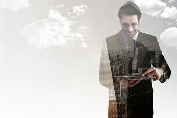 Wall Mural - Businessman standing while using a tablet pc against low angle view of skyscrapers