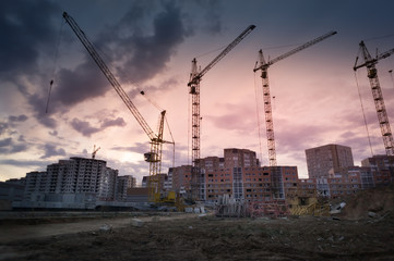 Industrial landscape with silhouettes of cranes over sunset