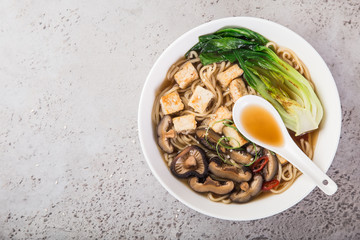 asian vegan noodle soup with tofu cheese,shiitake mushroms and pak choi in white bowl