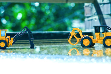 Two yellow excavator are playing in the yard with a little water after spring rain.