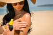 Close - up of Sexy asian woman are Spray Sunscreen , lotion or sunblock to body for prevent UV rays from sunlight Before the sun bathing in the summer or Vacation with sea and bluesky bckground.