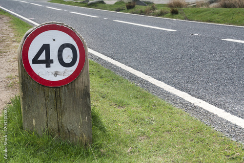 Fotografía Speed limit sign on grass verge by side of road