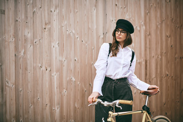 Wall Mural - Portrait of beautiful brunette holding bicycle. Wooden background.