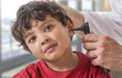 © JPC-PROD - A pediatrician examining his boy patient's ear at doctor's office