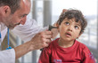 © JPC-PROD - A pediatrician examining his boy patient's ear at doctor's office