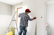 © artursfoto - Glueing wallpapers at home. Young man, worker is putting up wallpapers on the wall. Home renovation concept